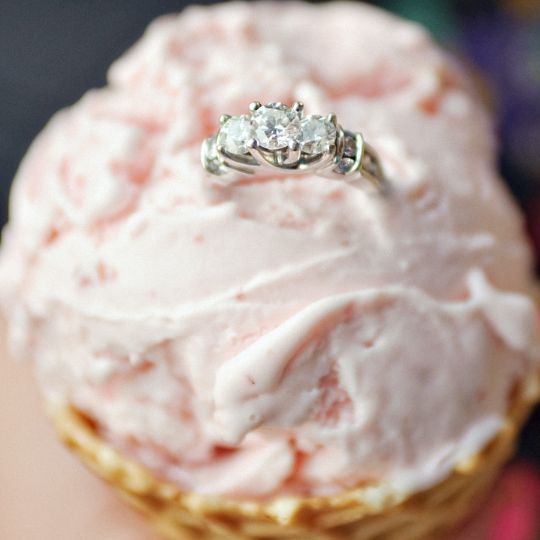 Pale
pink ice cream in a waffle cone. A three diamond
engagement ring sits on top of the ice cream.