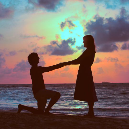 Proposal against a sunset sky. One person
kneeling on one knee.