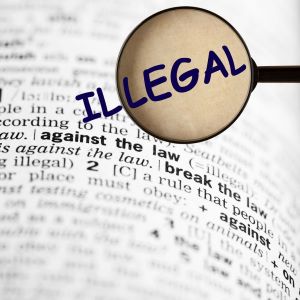 Dictionary pages with phrase Against the Law
highlighted. Magnifying glass and sthe word
Illegal