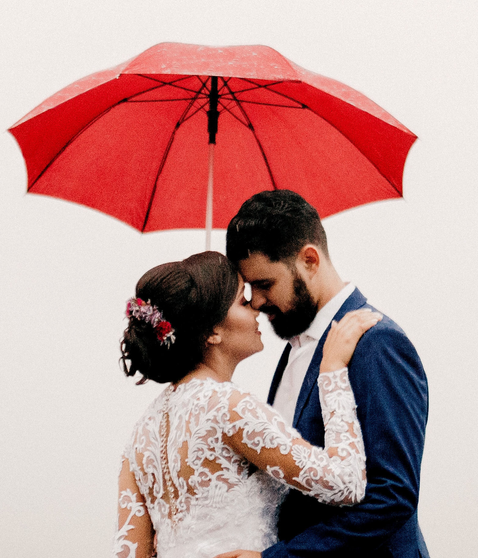 Bride and Groom embracing under a red
umbrella