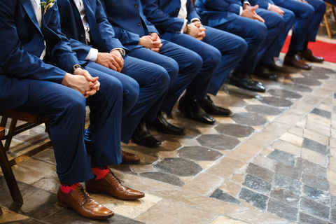 Groomsmen wearing blue
suits and brown shoes seated at front of wedding
ceremony