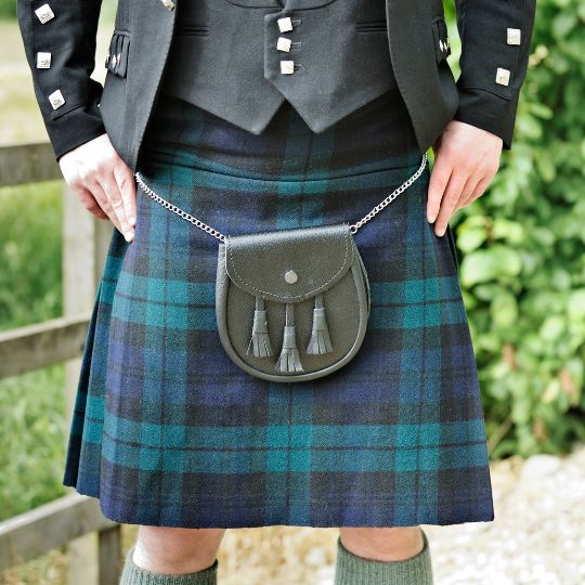 Man
standing with his legs slightly apart and his
hands on his hips. He is wearing a kilt, and a
Prince Charlie jacket and waistcoat