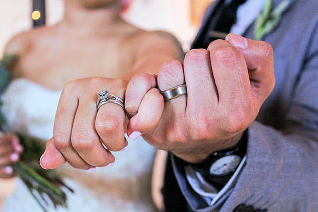 Couple's hands doing a pinky promise with
wedding rings on left hands