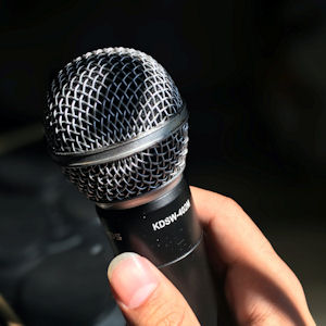 Hand holding a microphone against a dark
background